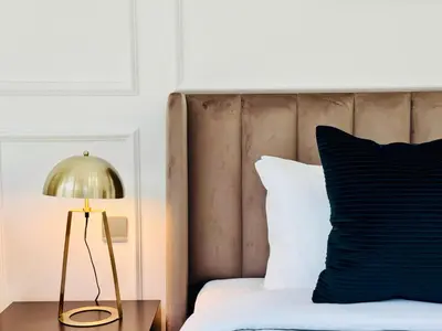 a bed with a gold lamp and a black pillow at Venduras Homes -Grande Tower, Downtown Dubai, Burj Khalifa & Fountain Views in Dubai