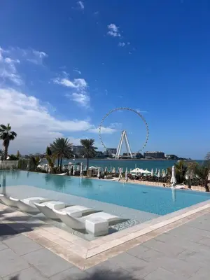 a swimming pool with chairs and a ferris wheel in the background at La Vie JBR Beatiful 1 Bed Seafront in Dubai