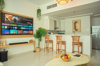 a kitchen with a bar with stools and a tv at Stilvolle Wohnung im Herzen von Dubai in Dubai