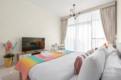 a bedroom with a large bed with a rainbow blanket at Luxury Studio in DAMAC Hills with Premium Amenities in Dubai