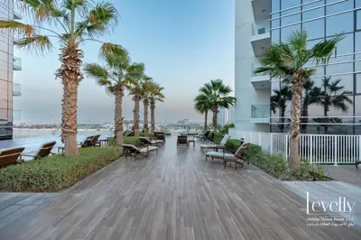 a walkway with chairs and palm trees on a building at Luxury Studio in DAMAC Hills with Premium Amenities in Dubai