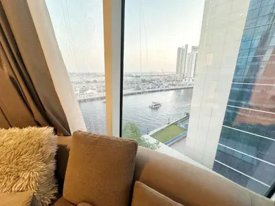 a couch in a room with a large window at Modern & Bright Canal View 2BR Near Dubai Mall by Vibel in Dubai