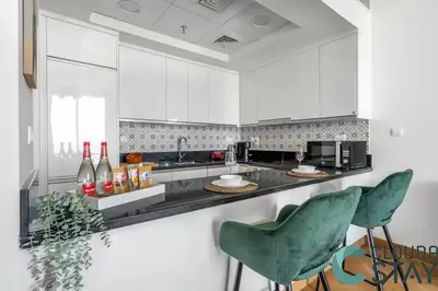 a kitchen with white cabinets and green chairs at Cloud 9 - Luxurious 1 Bedroom Apartment in Business Bay in Dubai