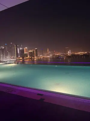 a large swimming pool with a city skyline at night at Charming Studio in Seven Palm with Balcony Rooftop Floor in Dubai
