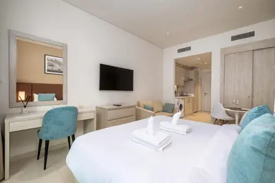 a bedroom with a white bed and a desk and chairs at Charming Studio in Seven Palm with Balcony Rooftop Floor in Dubai