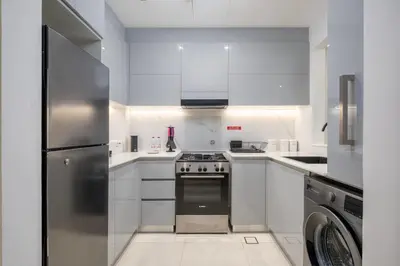 a white kitchen with a stove and a refrigerator at Chic 1 Bed in Creek Side with Terrace in Dubai