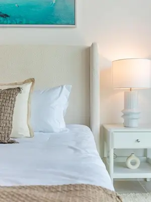 a bedroom with a bed with a white nightstand and a lamp at the Byron Bay condo in Dubai