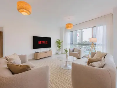 a living room with two chairs and a tv at the Byron Bay condo in Dubai