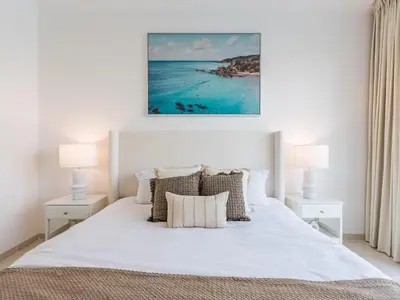 a bedroom with a large white bed with two lamps at the Byron Bay condo in Dubai