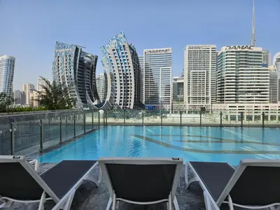 a swimming pool with two chairs and a city skyline at Business Bay Studio Binghatti Canal with Terrace in Dubai