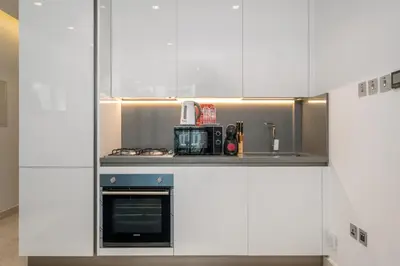 a kitchen with white cabinets and a stove top oven at Downtown Apartment Studio near Burj Khalifa in Dubai