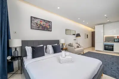 a bedroom with a large white bed and a living room at Downtown Apartment Studio near Burj Khalifa in Dubai