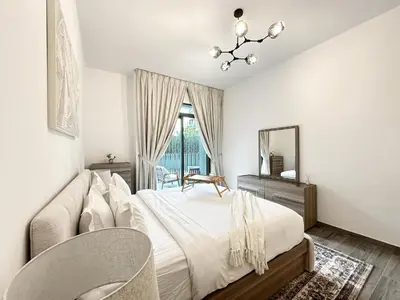 a bedroom with a bed and a chair and a mirror at Super Spacious 2BR with Designer Touch in Dubai