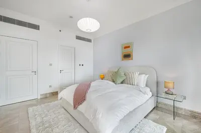 a white bedroom with a large bed and a table at Daniels 2BR at Fairmont South The Palm Jumeirah in Dubai