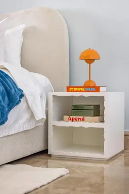 a bedside table with books on it next to a bed at Daniels 2BR at Fairmont South The Palm Jumeirah in Dubai