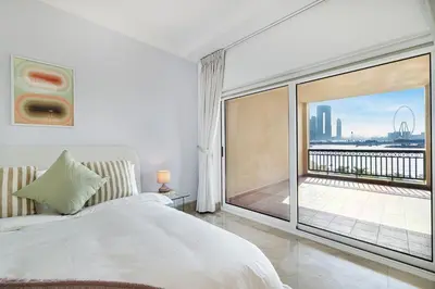 a bedroom with a large white bed and a balcony at Daniels 2BR at Fairmont South The Palm Jumeirah in Dubai