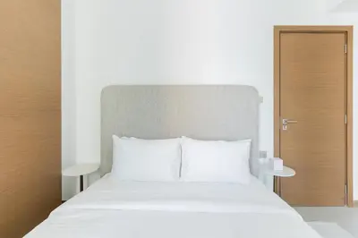 a white bed with white pillows and a wooden door at DAYF-DAN Missoni Apartment with Private Lift in Business Bay in Dubai