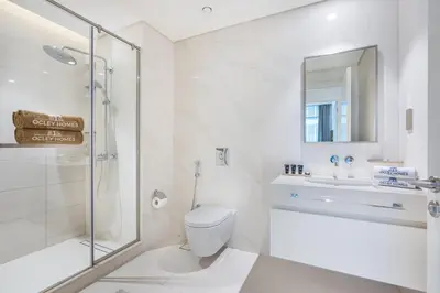 a white bathroom with a shower and a toilet and a sink at Stunning Beachfront Home with Panoramic Sea Views in Dubai
