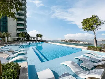 a swimming pool with white chairs and a building at Stunning Beachfront Home with Panoramic Sea Views in Dubai