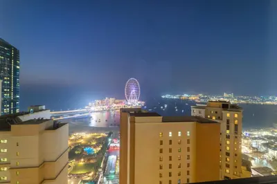 a city at night with a ferris wheel in the distance at Elegant 2BR with Seaview in JBR l Walk to the Beach in Dubai