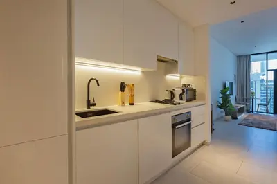 a white kitchen with a sink and a stove at Burj & Beyond - Luxury Stay with Burj Khalifa View in Dubai