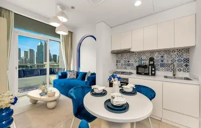 a kitchen and living room with blue chairs and a table at Luxury Apartment with Balcony & Full Burj Khalifa View by Dejaview Stays in Dubai