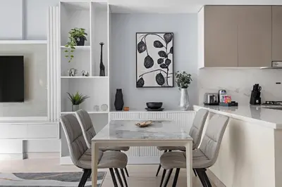 a white kitchen with a white table and chairs at 1BR Azizi Riviera B7, Pool View in Dubai