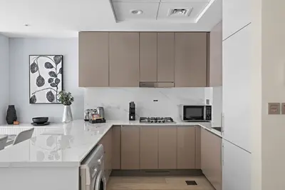 a kitchen with white cabinets and a counter top at 1BR Azizi Riviera B7, Pool View in Dubai