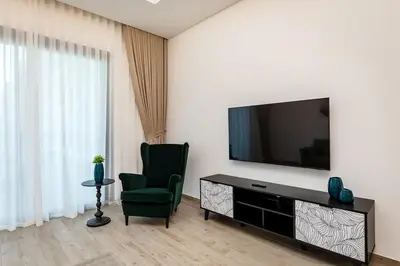 a living room with a television and a green chair at City Walk Green Planet View 1Br in Dubai