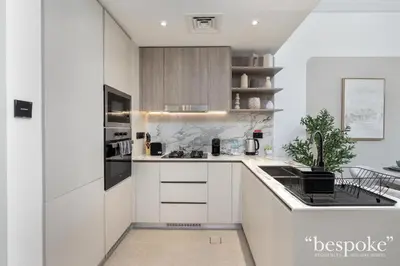 a kitchen with white cabinets and a counter top at Bespoke Holiday Homes - Stylish 1-BR Apartment in Oxford Terraces, JVC in Dubai
