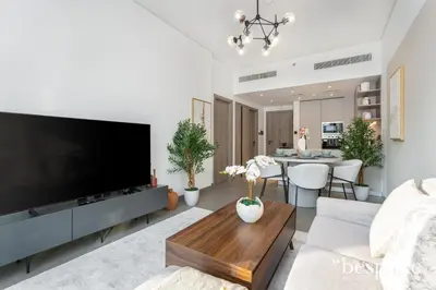 a living room with a large flat screen tv at Bespoke Holiday Homes - Stylish 1-BR Apartment in Oxford Terraces, JVC in Dubai
