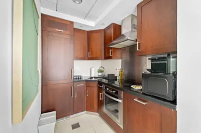 a large kitchen with wooden cabinets and appliances at Silkhaus Modern Studio with Burj Khalifa View in Dubai