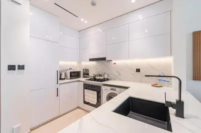 a kitchen with white cabinets and a sink at Smart living I High speed wi-fi I City view in Dubai