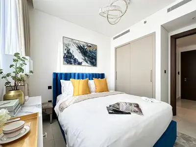 a bedroom with a large bed with a blue headboard at Trophy - Elegant Cozy 1Bdr in Sobha Hartland in Dubai