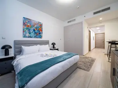 a bedroom with a large bed with two candles on it at Stylish Studio Living in the Heart of JVC in Dubai