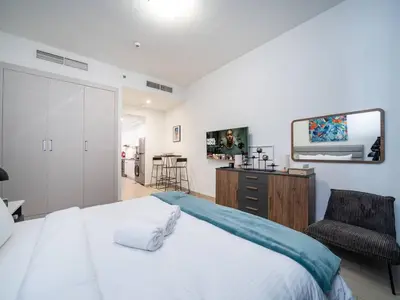 a bedroom with a bed and a mirror and a chair at Stylish Studio Living in the Heart of JVC in Dubai