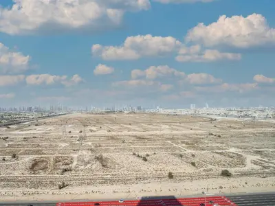 an empty field with a city in the background at Stylish Studio Living in the Heart of JVC in Dubai