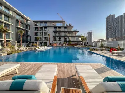 a large swimming pool with chaise lounge chairs in a building at GuestReady - Glamorous retreat in JVC in Dubai