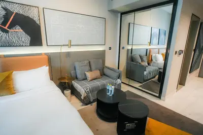 a bedroom with a bed and a couch and a mirror at Stylish Studio, MAG 318 in Dubai
