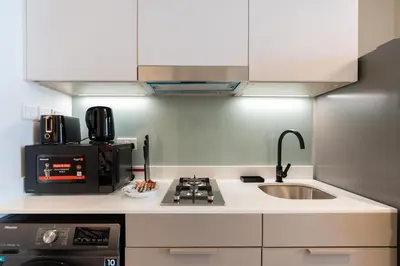 a kitchen with a sink and a microwave at Vacay Lettings - Spacious Studio Apartment - Production City in Dubai