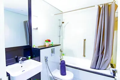 a bathroom with a sink and a shower and a toilet at Luxurious 1bhk in Cour Jardin in Dubai