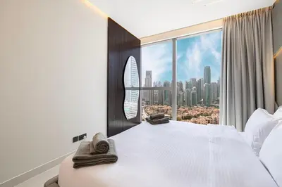a bedroom with a large white bed and a large window at Modern Stylish 2 Bedroom Apartment with Burj Khalifa View in Dubai