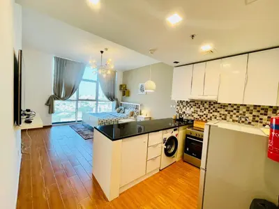 a kitchen with white cabinets and black counter tops at Studio apartment in jumeriah village triangle district 2 in Dubai