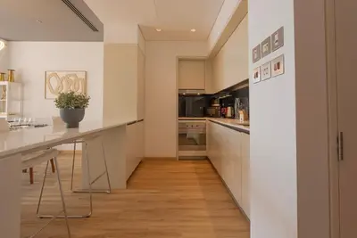 a kitchen with white cabinets and a long counter at Stunning Burj Khalifa & Downtown Views - Elegant 1BR in The Iconic Index Tower in Dubai
