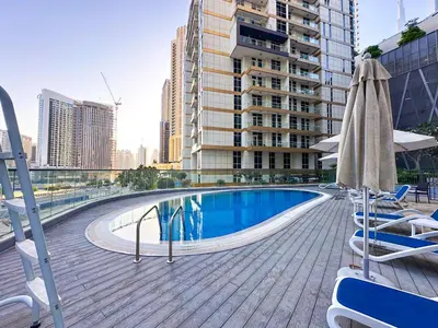 a swimming pool on a deck with chairs and umbrellas at Elegant 1BR in Dunya Tower, Downtown Dubai 12AB10 in Dubai