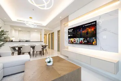 a living room with a tv on a wall at 5Star Stunning 2BR BURJ Khalifa View with Infinity Pool in Dubai