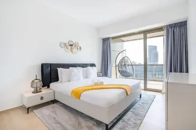 a white bedroom with a large bed and a window at RH -Luxury 1BR, Large Balcony & High-End Interiors, Downtown in Dubai
