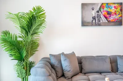 a living room with a couch and a palm tree at RH -Luxury 1BR, Large Balcony & High-End Interiors, Downtown in Dubai