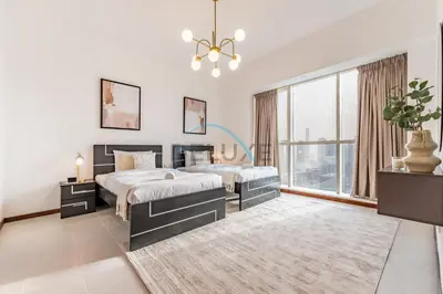 a bedroom with two beds and a large window at Stunning 2BR with Assistant Room in MAG 214, Jumeirah Lake Towers by Deluxe Holiday Homes in Dubai