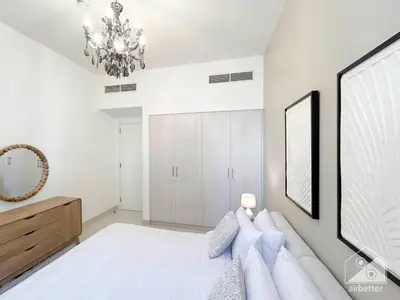 a white bedroom with a large bed and a chandelier at Luxury Design & Stunning Views in Dubai Hills in Dubai